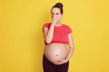Kobieta w ciąży zatyka nos, cierpiąc z powodu śmierdzących gazów.