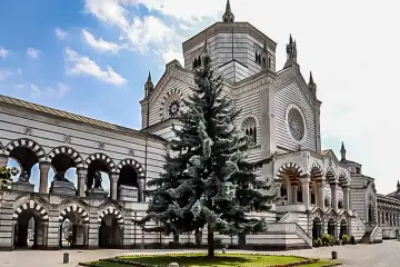 Imponujący cmentarz monumentalny w Mediolanie z majestatyczną budowlą i okazałą choinką na pierwszym planie.
