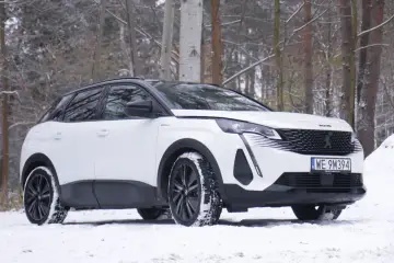 Biały Peugeot 3008 hybryda na śniegu, gotowy na zimowe przygody w lesie.