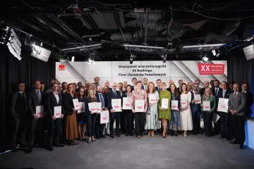 Grupa nagrodzonych osób z dyplomami na tle sceny z logo rankingu.