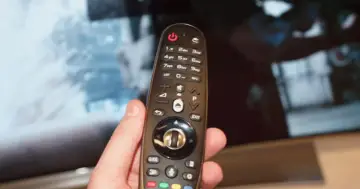 Dłoń trzyma pilota od telewizora. Zastanawiasz się, czy można odbierać telewizję naziemną bez anteny? Ten pilot może pomóc Ci znaleźć odpowiedź.
