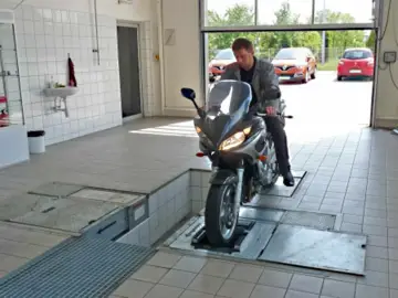 Mężczyzna na motorowerze na stanowisku diagnostycznym. Zastanawiasz się, ile kosztuje przegląd motoroweru?
