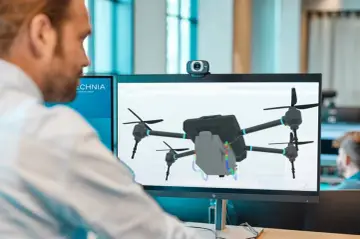 Mężczyzna pracuje przy komputerze, na ekranie widoczny jest model drona w programie symulacyjnym.