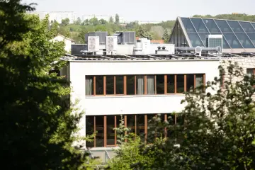 Nowe budynki od września 2026 będą musiały posiadać instalację fotowoltaiczną. Na dachu budynku widać panele i klimatyzatory.