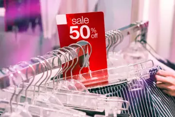 Czerwona metka "sale 50% off" na wieszakach. Unikaj skutków nieprzemyślanych zakupów dekoracji sezonowych, planując świadomie.