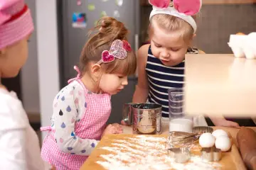 Dwie dziewczynki w fartuszkach pieką ciasto. Zastanawiają się, co zamiast mąki ziemniaczanej do bezy.