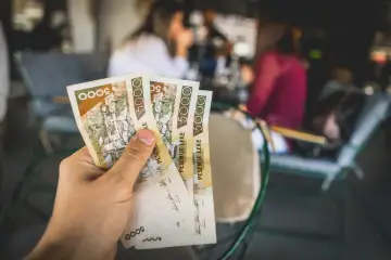 Dłoń trzyma banknoty 5000 leków. To jest jaka waluta w Albanii, idealna na wakacyjne zakupy.