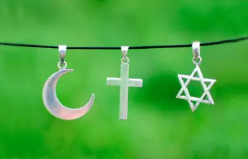 Srebrny półksiężyc, krzyż i gwiazda Dawida wiszą obok siebie, symbolizując pokój między islamem a chrześcijaństwem.