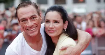 Jean-Claude Van Damme z uśmiechem obejmuje swoją żonę.