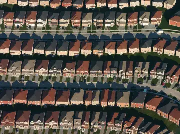 Rzędy identycznych domów z dachami w różnych kolorach, symbolizujące suburbanizację.