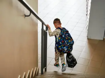 Chłopiec z plecakiem wspina się po schodach. Każdy uczeń to przyszłość, a subwencja oświatowa na ucznia wspiera tę drogę.