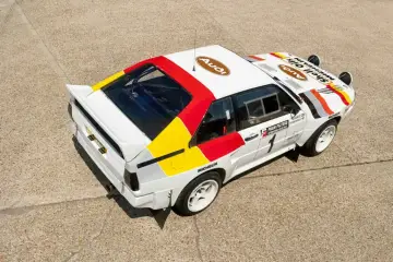 Biały rajdowy **Audi quattro S1** z kolorowymi pasami i logotypami sponsorów, gotowy do podboju szutrowych tras.