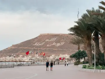 Spacerem po promenadzie w Agadirze, z widokiem na miasto i napisem na wzgórzu. Czy Agadir jest bezpieczny? Tak, wygląda na spokojne miejsce.