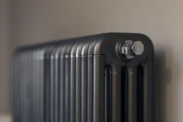 Gros plan sur un radiateur bain d'huile noir, avec un bouchon chromé visible. Un élément clé pour gérer la consommation d'énergie.