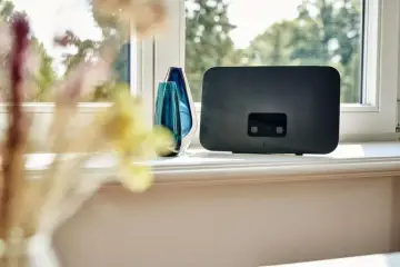 Nowoczesna antena do internetu mobilnego, elegancko ustawiona na parapecie obok ozdobnych wazonów.
