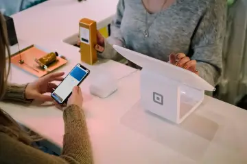 Kobieta płaci telefonem, ekran pokazuje "Face ID". Czy można cofnąć blik? Zakup kosmetyku w sklepie.