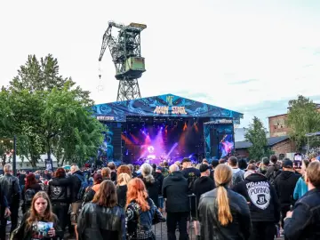 Tłum fanów na festiwalu Mystic Festival w Gdańsku. W tle scena z napisem "Main Stage" i zabytkowy dźwig. Wiele takich festiwali w Polsce przyciąga miłośników muzyki.