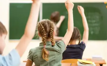 Uczniowie z podniesionymi rękami, ciekawi lekcji. Czyżby to był moment, od której klasy drugi język obcy?