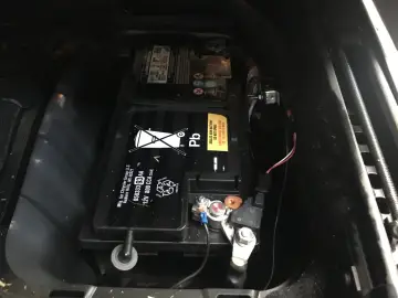 Akumulator w Jeep Grand Cherokee WK2 znajduje się w bagażniku, pod podłogą. Widoczny jest czarny akumulator z oznaczeniem "Pb".