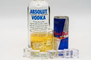 Butelka wódki Absolut, szklanka z drinkiem i puszka Red Bulla. Idealny drink z energetykiem na upalne dni.
