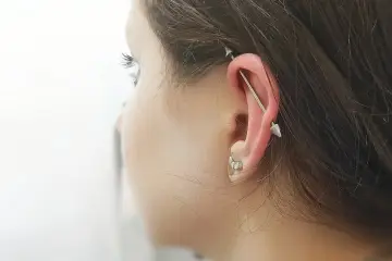 Industrialny piercing ucha z długą sztangą i dwoma stożkami. To przykład, co to jest piercing, który ozdabia ciało.