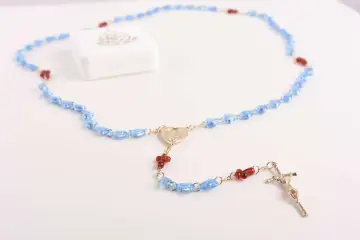 Niebieski różaniec z czerwonymi akcentami i krzyżem. Wybór różańca na roczek symbolizuje błogosławieństwo i duchową drogę.