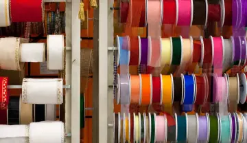 Variedad de tipos de cintas de tela en rollos, con colores y texturas diversas, ideales para manualidades y decoración.