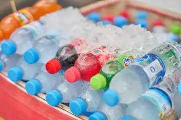 Butelki z napojami, w tym Fanta, schłodzone w lodzie. Czy woda ma kalorie? Czysta woda nie, ale te słodkie napoje już tak.