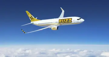 Samolot Buzz, należący do Ryanair, leci nad chmurami. Idealny na wakacje, zabierze Twój bagaż w słoneczne miejsce.