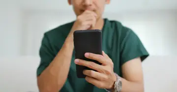 Mężczyzna zamyślony nad telefonem, szuka informacji jak włączyć autokorektę Samsung.