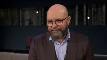 Szymon Bobrowski w garniturze i okularach, opowiada o swoich filmach, serialach i programach.