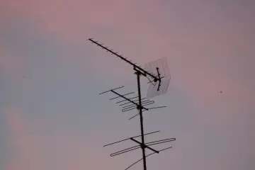 Antena telewizyjna na tle różowego nieba. Dowiedz się, jak podłączyć kabel antenowy do anteny, aby cieszyć się najlepszym odbiorem.