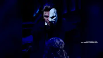 Upiór w operze w białej masce, z mrocznym spojrzeniem, w dramatycznym świetle.