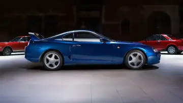 Niebieska Toyota Supra w towarzystwie czerwonych klasyków. Sprawdź aktualną toyota supra cena i znajdź swój wymarzony samochód.