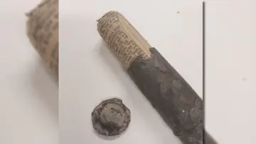 Zardzewiała metalowa kapsuła czasu z zrolowanym dokumentem w środku, obok leży zakrętka.