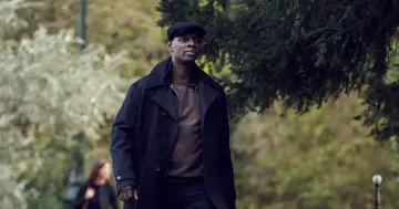 Omar Sy w eleganckim płaszczu i kaszkiecie, jakby prosto z jego filmów i seriali.