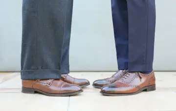 Długość spodni garniturowych: jeden model ma wywinięte nogawki, drugi gładkie. Eleganckie buty męskie.
