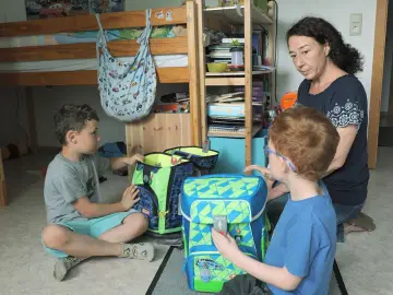 Mutter hilft ihren beiden Söhnen, Schultaschen zu packen. Ein Junge ist 16 Jahre alt.
