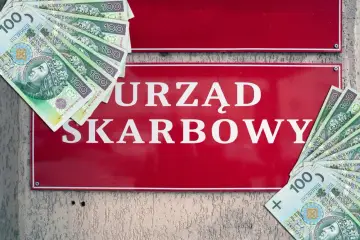 Ulga dla pracujących seniorów? Na czerwonej tablicy "URZĄD SKARBOWY" leżą polskie stuzłotówki.