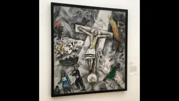 Obraz Chagalla przedstawia ukrzyżowanego Chrystusa pośród chaosu wojny, z płonącymi budynkami i żołnierzami.