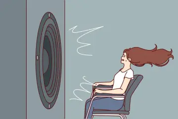 Une femme assise, les cheveux au vent, face à un haut-parleur. Le son est si fort qu'il en devient une force physique, illustrant la définition du décibel.