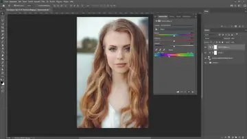 Portret młodej kobiety z falującymi włosami, edytowany w programie graficznym. Panel "Farbton/Sättigung" sugeruje, że zastosowano efekt **high key**.
