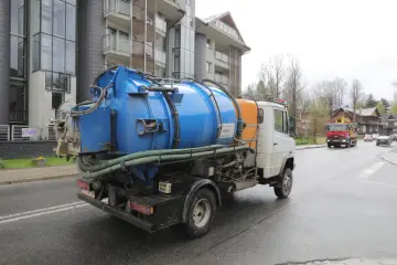 Ciężarówka z beczką do wywozu szamba na ulicy. Sprawdź wywóz szamba cennik, by poznać koszty usługi.
