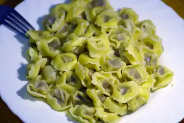 Porcja świeżo ugotowanego makaronu tortellini na białym talerzu. Zastanawiasz się, ile gotuje się makaron? Te wyglądają idealnie!