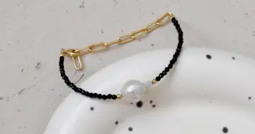 Elegancka bransoletka z czarnego onyksu i perły, z elementami złotej biżuterii. Czy onyks jest drogi? Ten wygląda na wart swojej ceny.