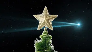 Złota gwiazda betlejemska na szczycie choinki, na tle nocnego nieba z jasną kometą.