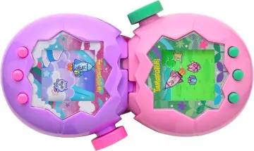 Dwa otwarte Tamagotchi: fioletowe z kosmicznym motywem i różowe z zielonym tłem. Na ekranach pikselowe postacie i rakiety.