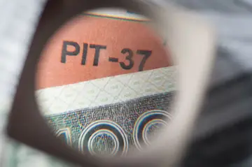 Pod lupą widać napis PIT-37 na tle banknotu 100 zł.