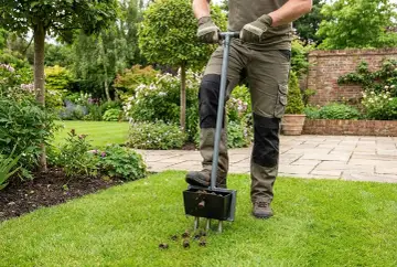 Gartenarbeit nach dem Winter: Ein Mann belüftet den Rasen mit einem speziellen Werkzeug, um ihn für die neue Saison vorzubereiten.