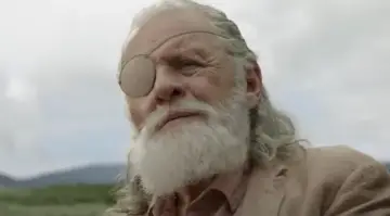 Anthony Hopkins w filmach, jako starszy mężczyzna z siwą brodą i opaską na oku, wpatruje się w dal.